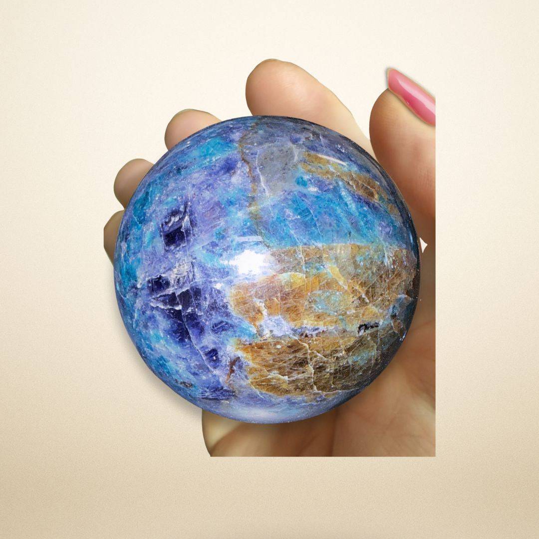 Hand holding 458g Trinity Stone Sphere with vivid blue, green, and brown hues of Fuchsite, Kyanite, and Garnet for metaphysical use or decor.