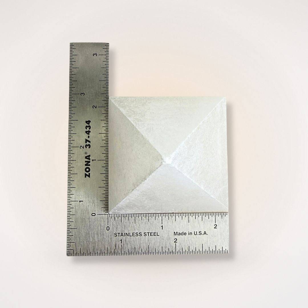 White Selenite Pyramid measured with ruler, approx. 150–200g, showcasing size for use in energy cleansing and mindful home décor settings.