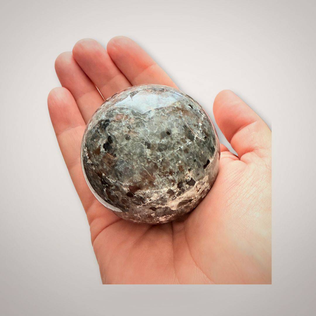 Polished UV Sodalite (Yooperlite) Sphere 58mm shown in hand for scale, emphasizing its compact size and collectible appeal.