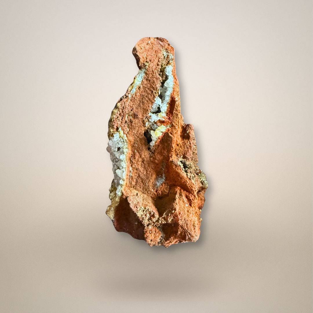 Side view of adamite with calcite on limonite showing open cavities, crystal-lined seams, and irregular oxidized matrix.