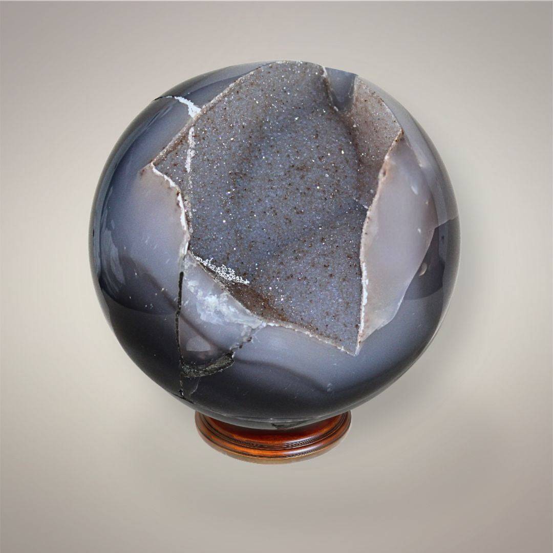 Large Agate druzy sphere from Brazil with polished gray-blue chalcedony exterior and sparkling exposed druzy crystal pocket.