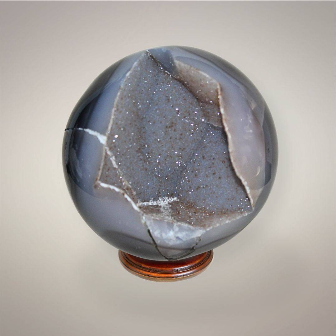 Agate druzy sphere showing a glittering druzy pocket framed by smoky gray chalcedony, exposed matrix, and polished agate banding.