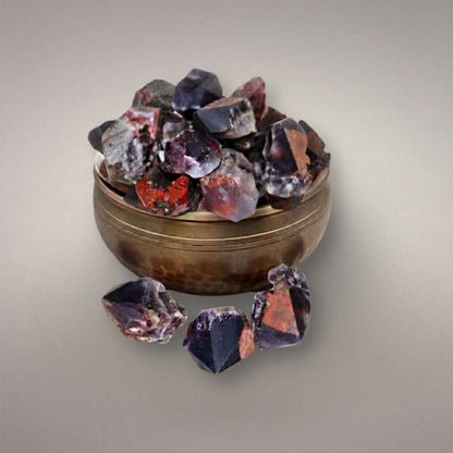 Alien Amethyst points from India displayed on a brass singing bowl, showing violet quartz with red hematite inclusions