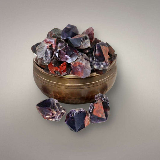 Alien Amethyst points from India displayed on a brass singing bowl, showing violet quartz with red hematite inclusions