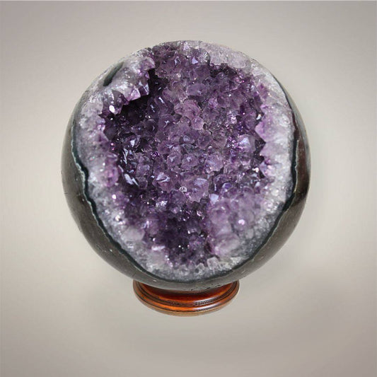 Large Amethyst geode sphere from Brazil with deep violet crystal points, polished dark outer shell, and open sparkling geode pocket.