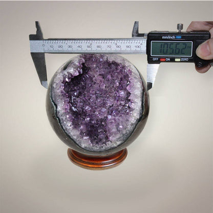 Large Brazilian Amethyst geode sphere measured with digital calipers at approximately 105.62 mm diameter.