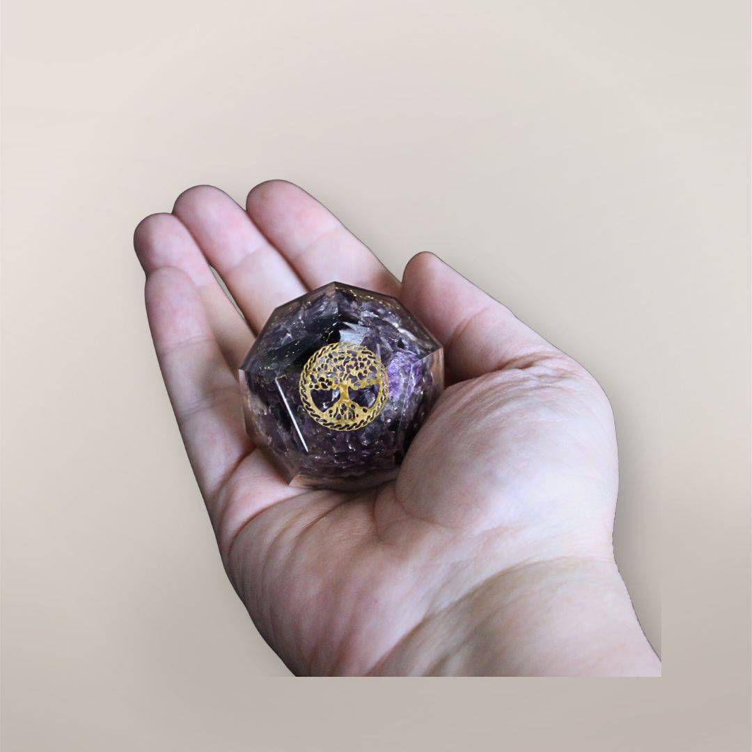 Two inch Amethyst orgonite dodecahedron with golden Tree of Life symbol resting in a hand to show size and scale