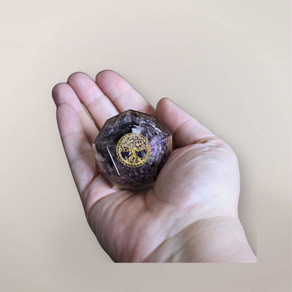 Two inch Amethyst orgonite dodecahedron with golden Tree of Life symbol resting in a hand to show size and scale