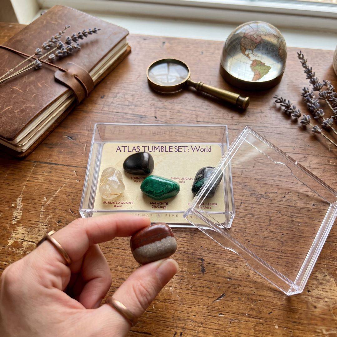 Open Atlas Tumble Set World collector case showing removable tumbled stones with Shiva Lingam held outside the display