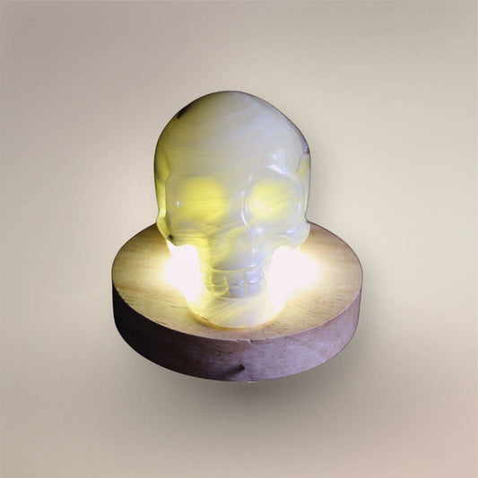 Front view of Mexican banded calcite skull illuminated from below, revealing translucent layered structure through the carving.