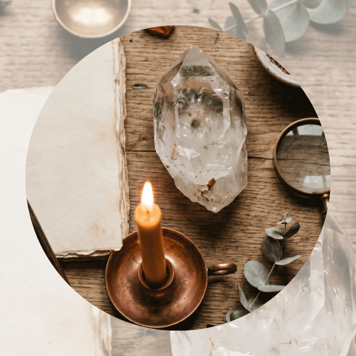 Crystal on a wooden board with a lit candle and eucalyptus leaves