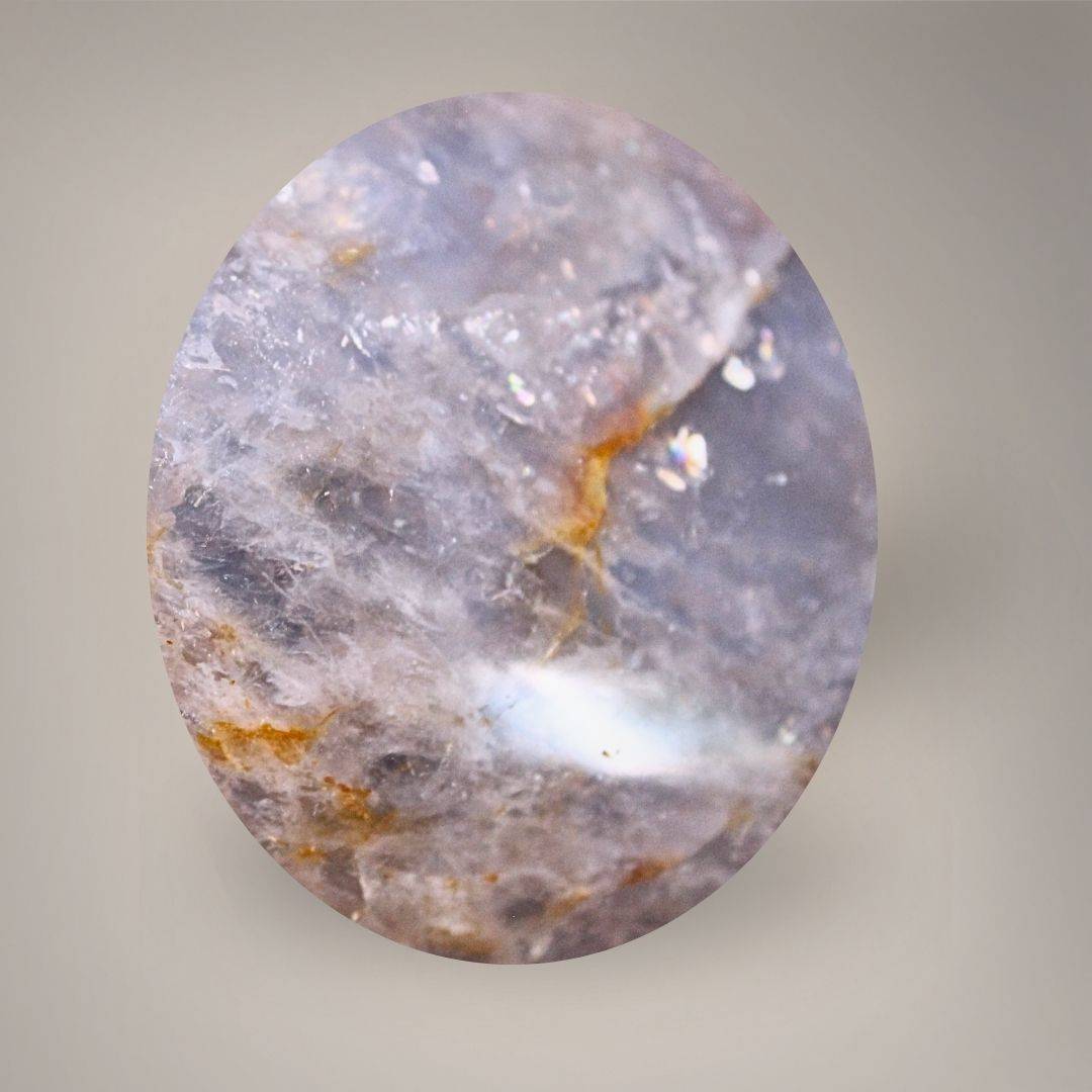 Close-up of Blue Rose Quartz showing translucent cloudy areas, fine fractures, and golden-ochre seams.
