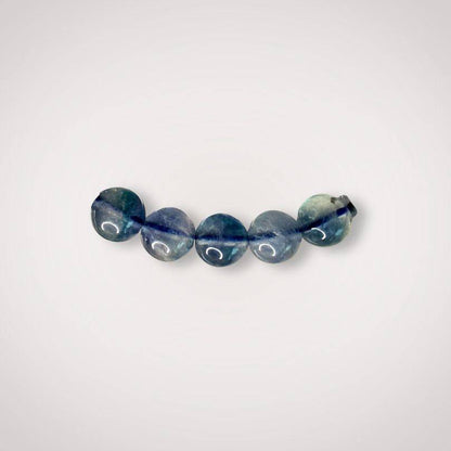 Close-up of five 7mm Blue Fluorite beads, emphasizing natural variations and smooth finish ideal for clarity and focus jewelry.