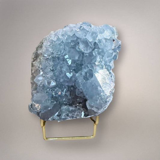 Sky blue celestine geode cluster with sparkling crystals on a gold stand, showcasing natural mineral formation for collectors and decor.