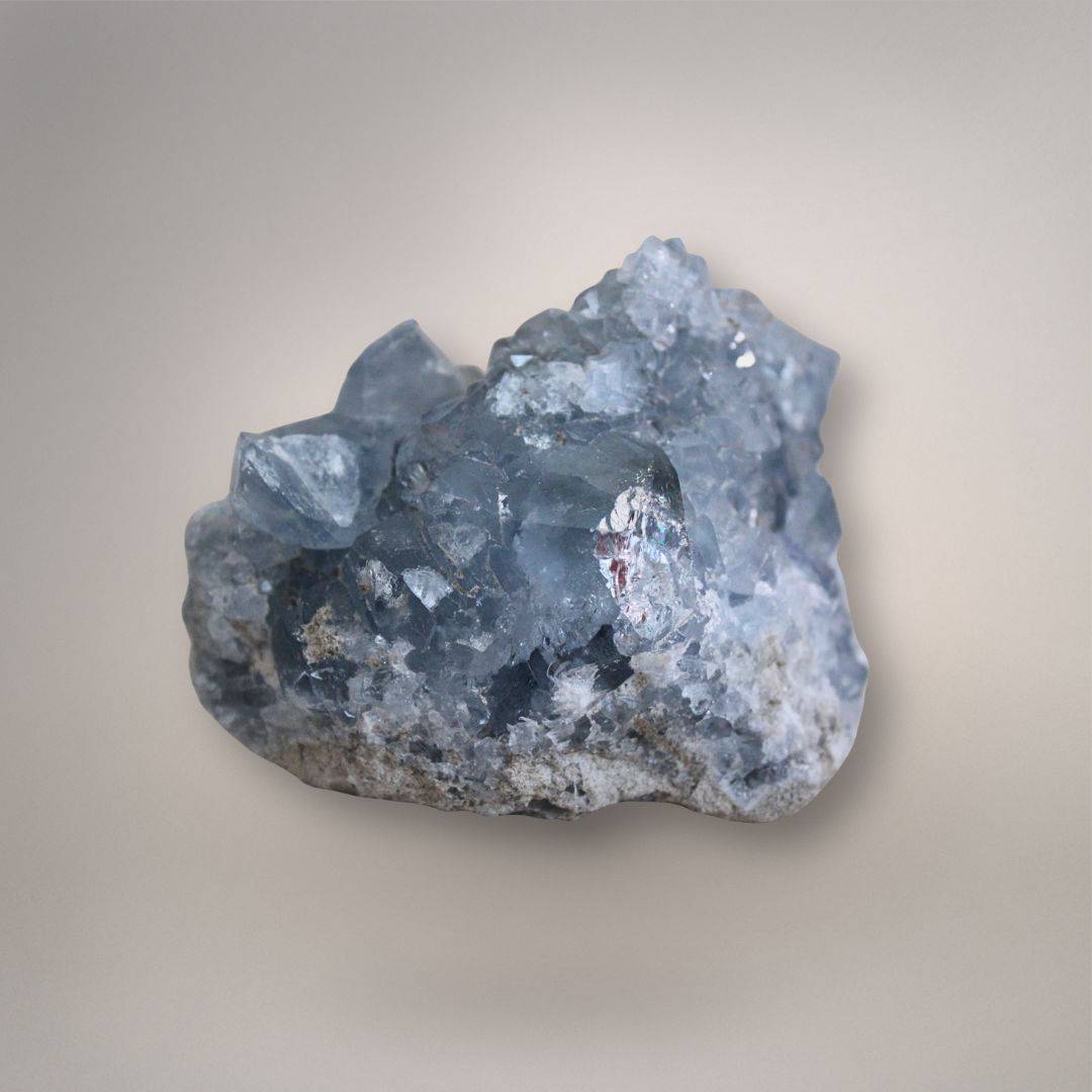 Raw Celestine mineral on beige surface