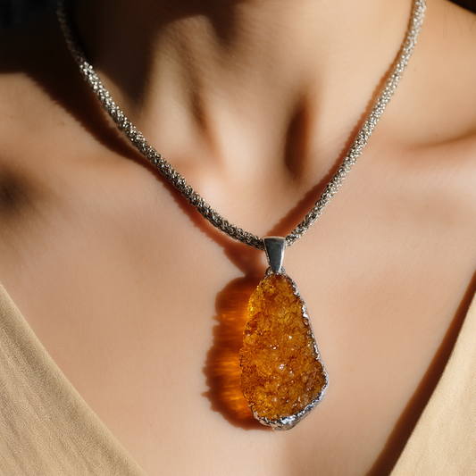 warm honey colored citrine pendant wrapped in silver hanging from a silver chain.