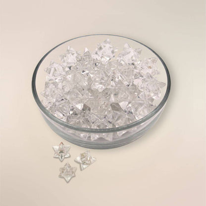 Glass bowl filled with polished Clear Quartz Merkaba stones from Brazil on a soft cream background.