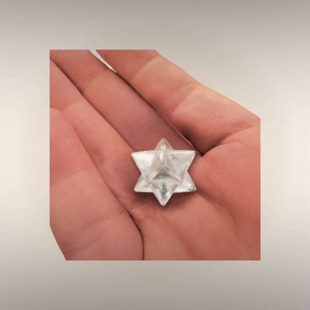 Clear Quartz Merkaba stone resting in a hand to show approximate 1 inch size.