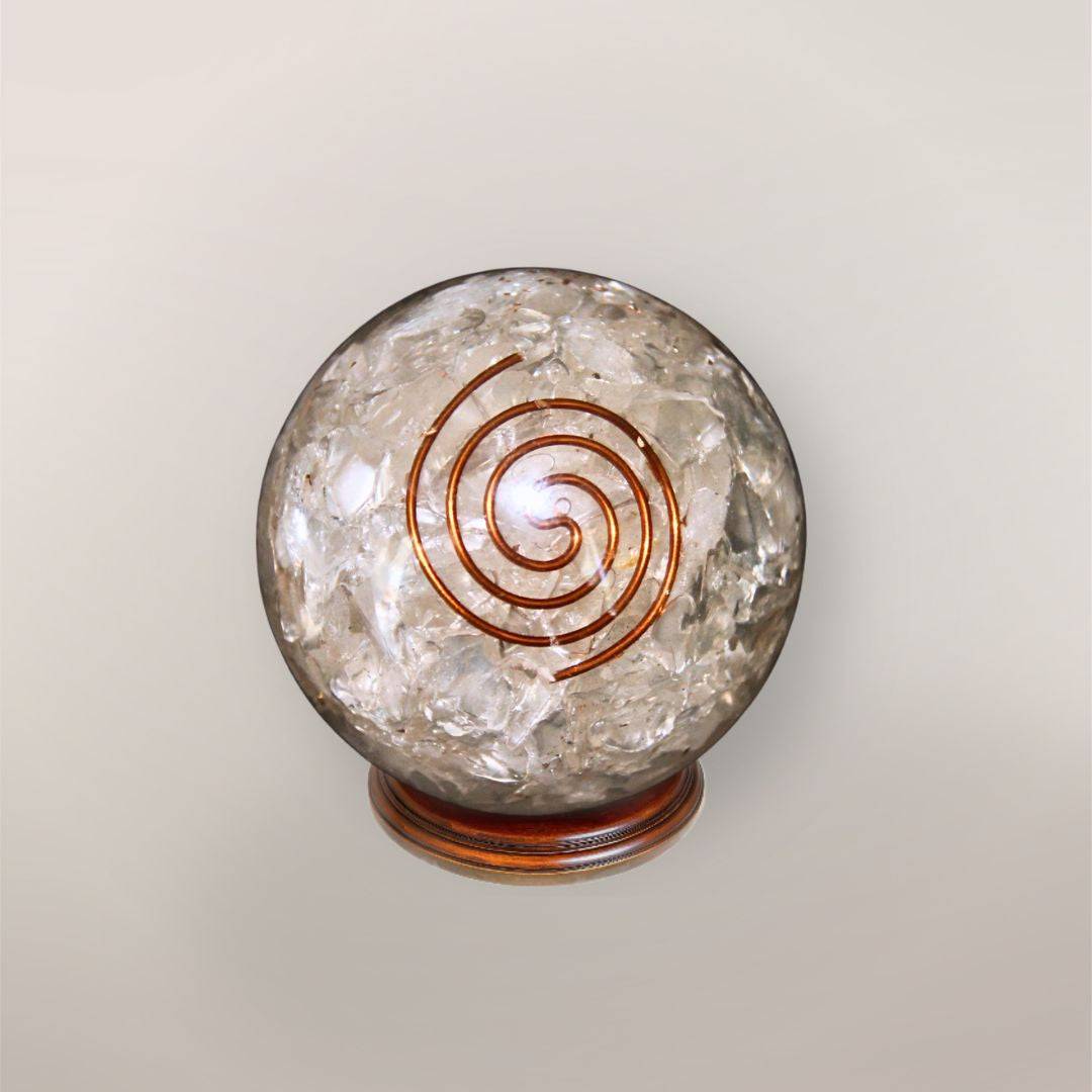 Clear quartz orgonite sphere with Himalayan quartz chips, copper spiral, and wood display stand