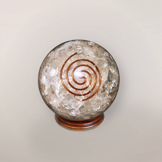 Clear quartz orgonite sphere with Himalayan quartz chips, copper spiral, and wood display stand