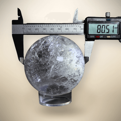  Madagascar Clear Quartz sphere measured at approximately 80.5 mm with digital calipers, showing natural internal veils and polished finish.

