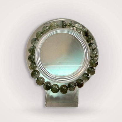 Lodolite (Garden Quartz) 8mm beaded bracelet displayed on a clear stand, showcasing natural inclusions for manifestation and growth.