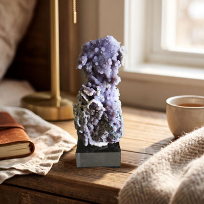 Tall 183g lavender Grape Agate cluster displayed on a black base beside a journal and cup in warm natural light