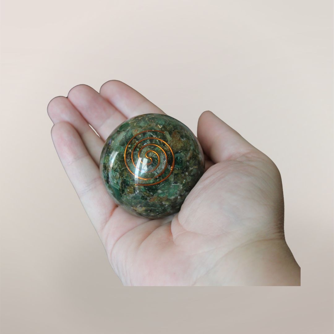 Two inch Green Aventurine orgonite sphere with copper spiral resting in a hand to show size and scale