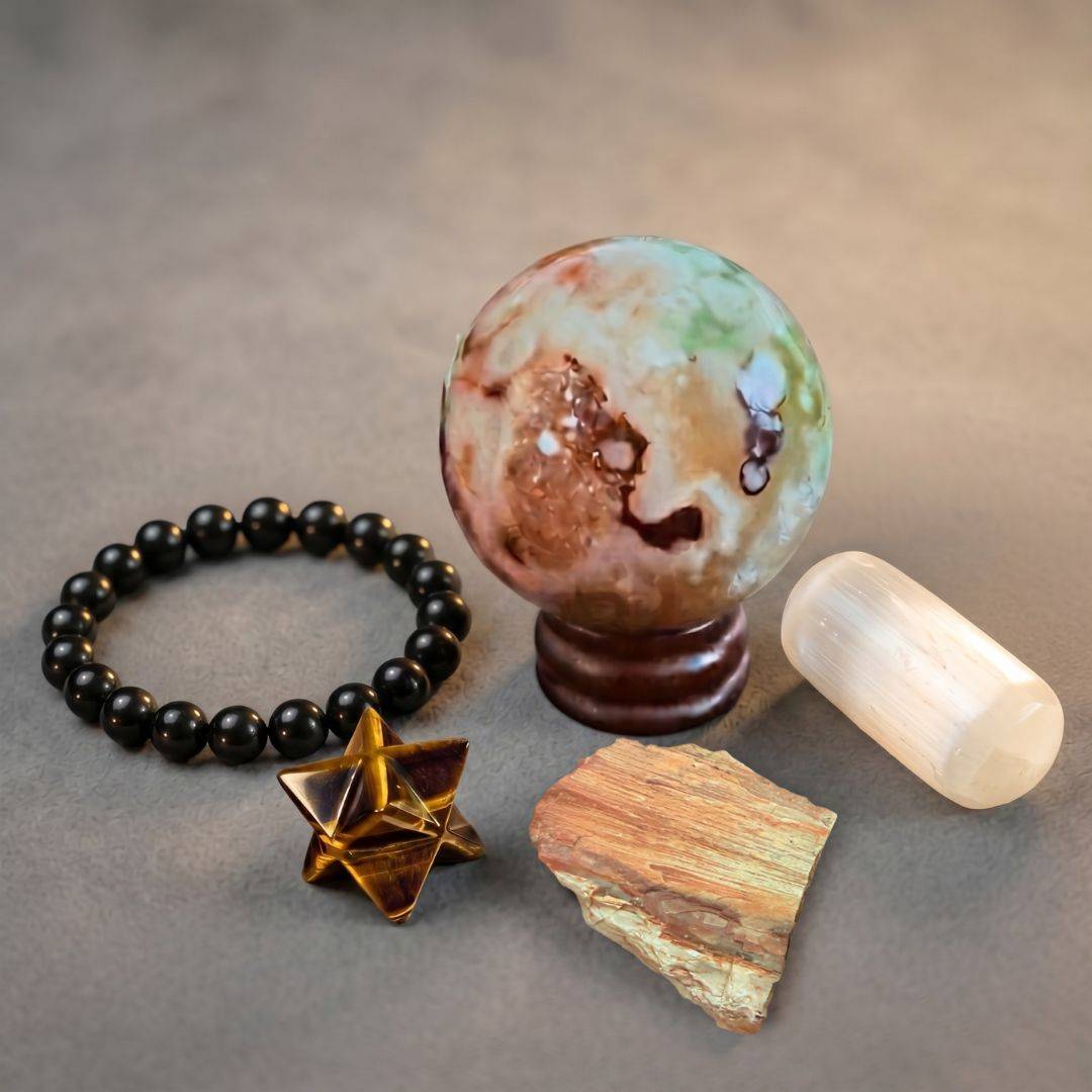 Grounded Energy Gift Set featuring a shungite bracelet, intuitively selected jasper sphere with wood stand, UV reactive petrified wood from Nevada, tiger's eye merkaba, and satin spar tumble arranged on a neutral background.