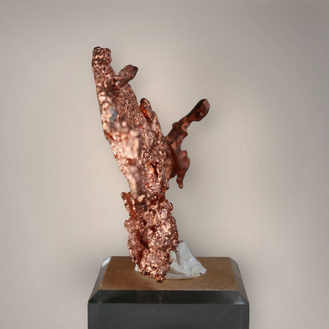 Side profile of native copper from China revealing its narrow branching structure, textured metallic surfaces, and acrylic display base.