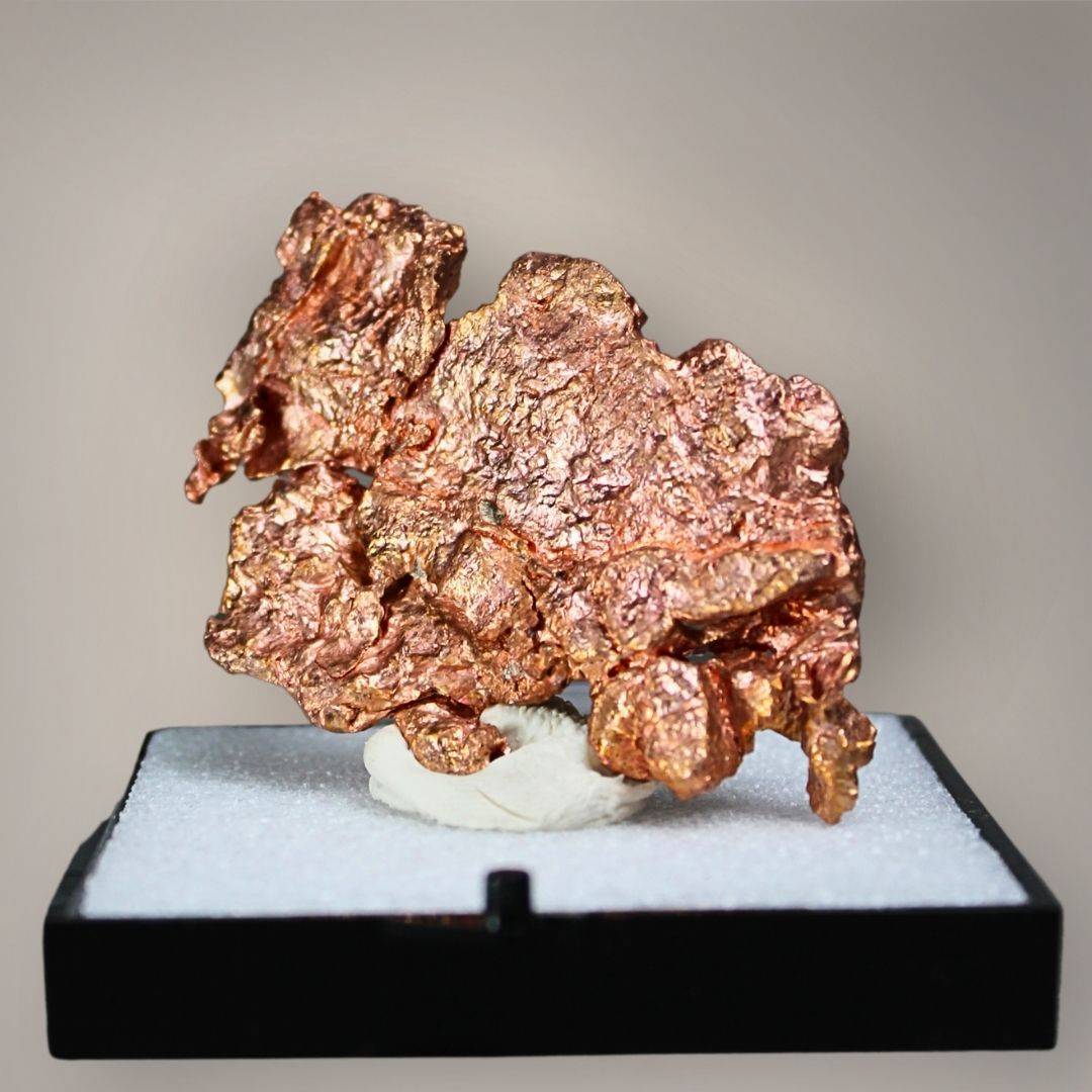 Native copper specimen from China featuring broad, interconnected copper-red growth, irregular crystalline projections, and reflective metallic surfaces displayed on a black perky base.