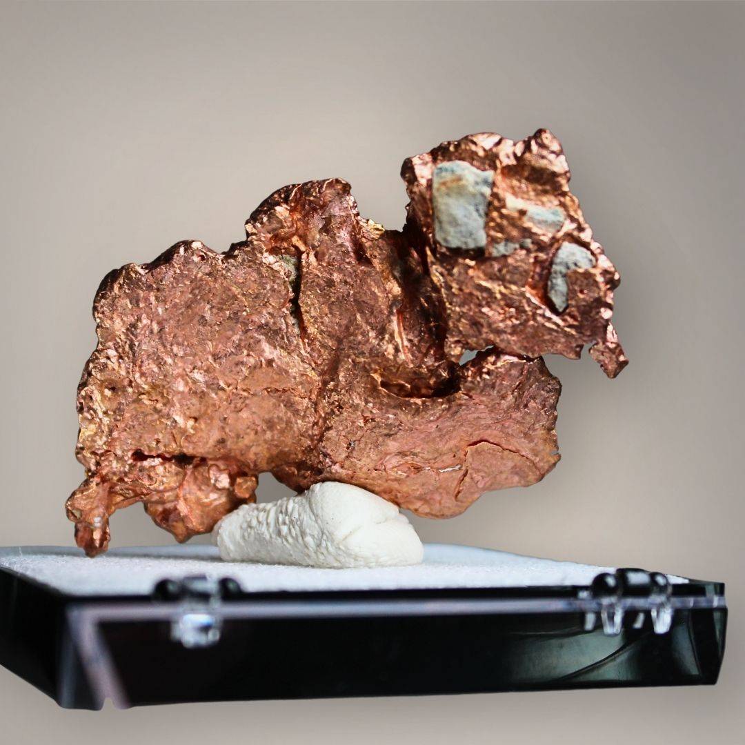 Reverse of Chinese native copper showing broad, flattened metallic surfaces, reddish-brown textures, irregular projections, and small gray-green mineral patches.