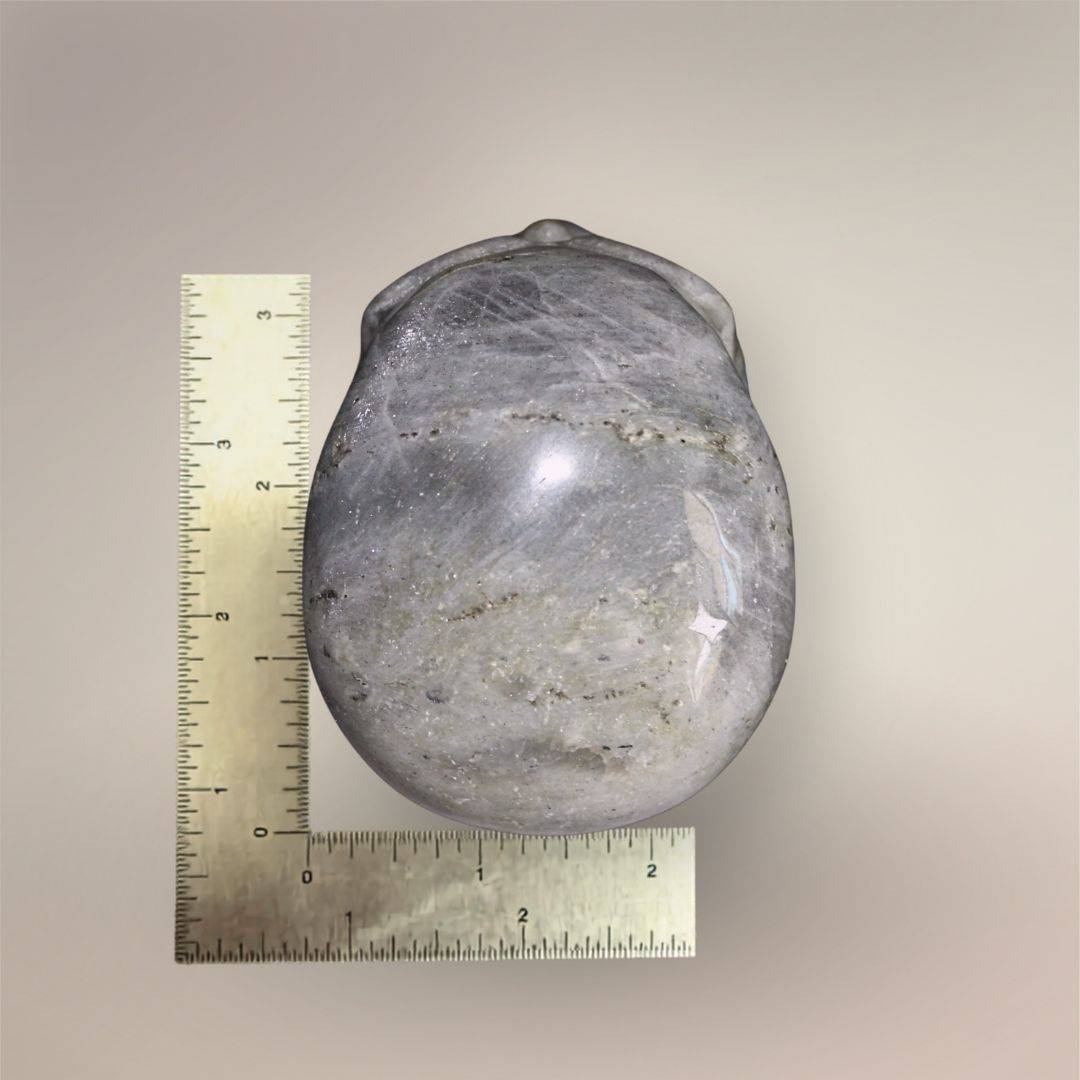 Rear view of 3.5-inch Labradorite skull beside rulers showing scale, gray feldspar structure, and natural mineral variation.