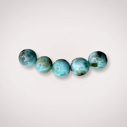 Close-up of five 7mm Larimar beads with natural blue and white marbling, emphasizing the bracelet’s serene energy and Dominican origin.
