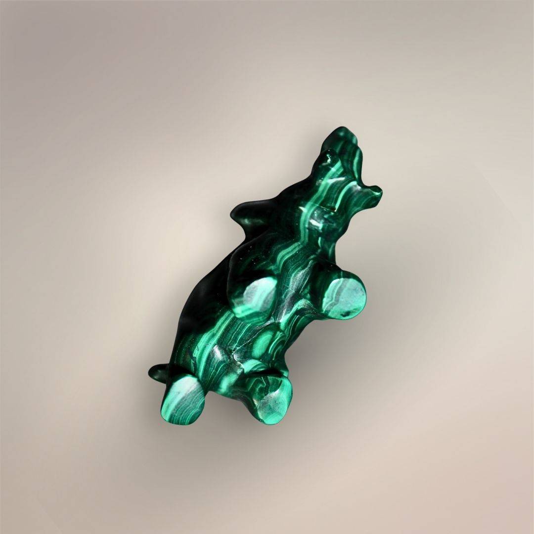 Bottom view of a polished Malachite elephant carving showing the underside, four rounded feet, raised trunk, and green banding.