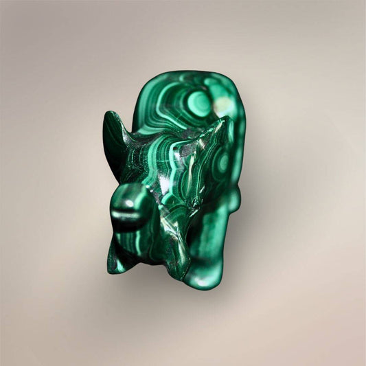 Front view of a polished Malachite elephant carving with a raised trunk, carved ears, rounded legs, and concentric green patterns.