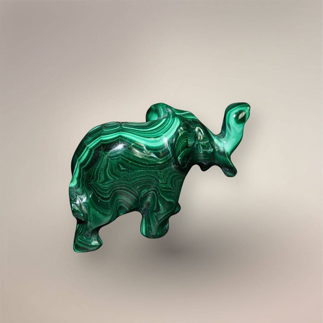 Reverse side view of a Malachite elephant carving showing layered dark and bright green banding across the body and raised trunk.