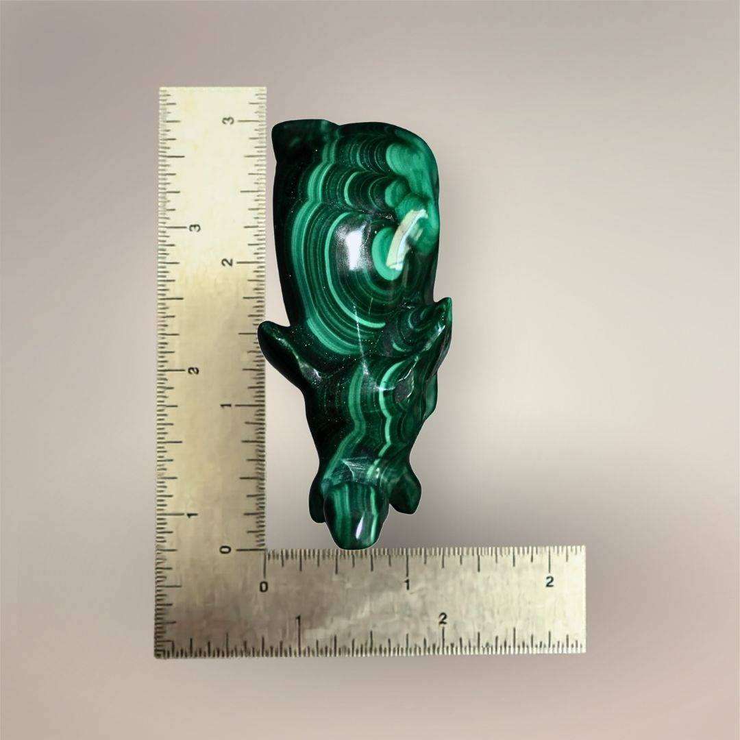 Malachite elephant carving beside inch rulers showing an approximate length of 3 inches and width under 1 inch.