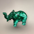 Side view of a polished Malachite elephant carving with a raised trunk, carved ear, rounded body, and circular green patterning.