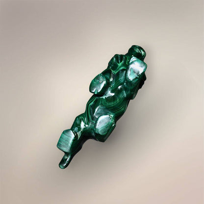 Bottom view of a polished Malachite lion carving showing curved green banding across the body.
