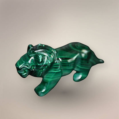 Side view of the hand-carved Malachite lion showing layered green bands across the mane, torso, legs, and tail.