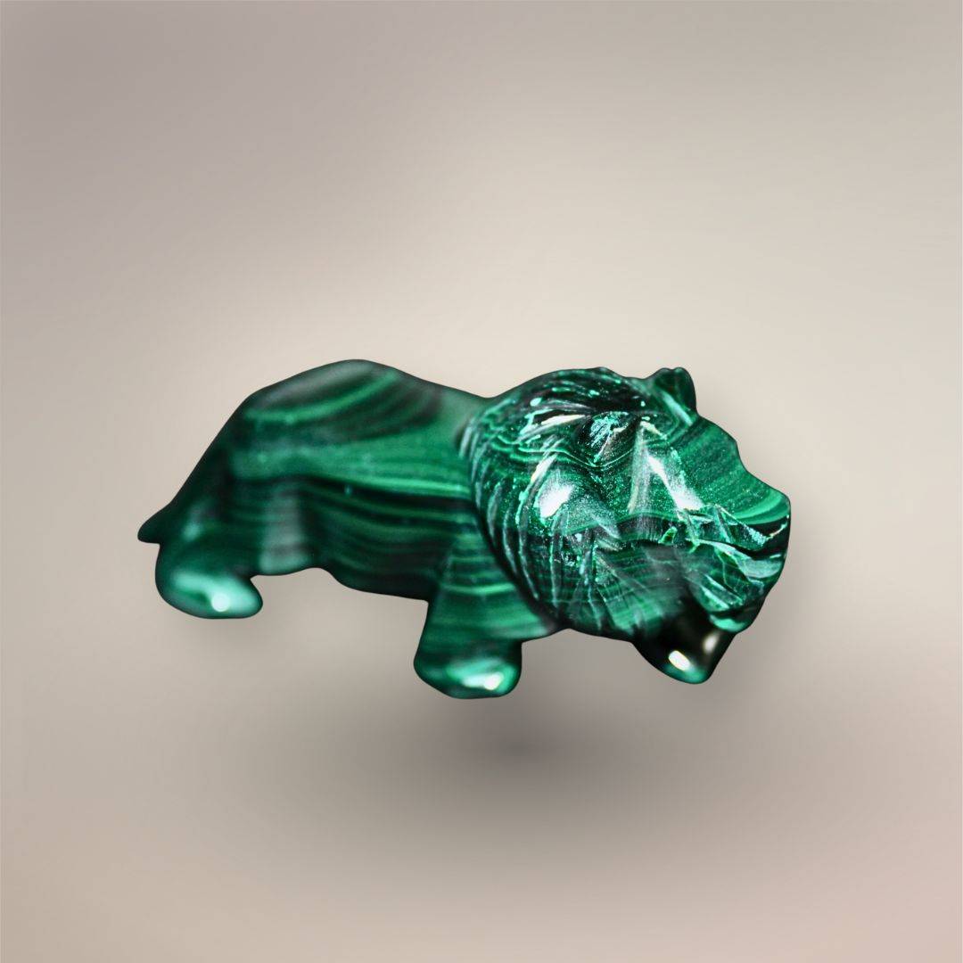 Reverse side view of the polished Malachite lion with carved facial features, rounded paws, and horizontal green banding.