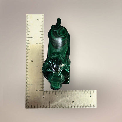Malachite lion carving beside inch rulers showing an approximate length of 3 inches and width under 1 inch.