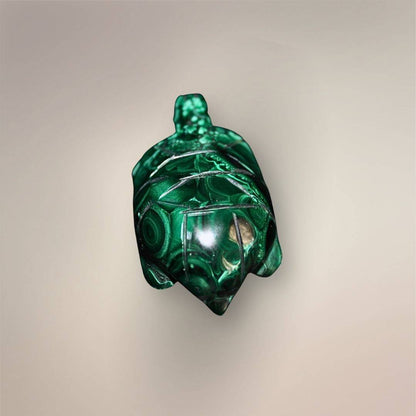 Back view of a polished Malachite turtle carving showing the domed shell, carved panel lines, and circular green banding.