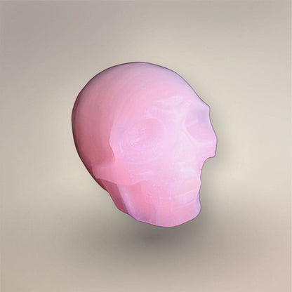 Mangano calcite skull displaying vivid pink fluorescence under UV light.