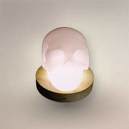 Pale pink mangano calcite skull from Mexico with polished carved facial details, on light stand