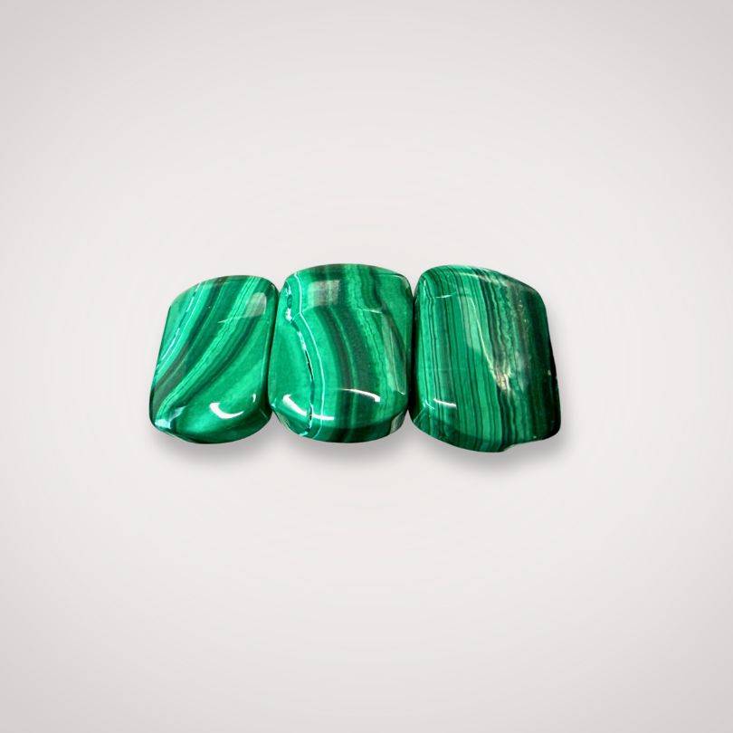 Close-up of three polished malachite flat beads 14×9mm with rich green banding, used in bracelets for transformation and protection.