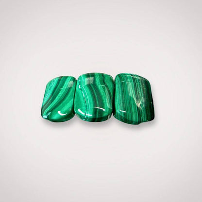 Close-up of three polished malachite flat beads 14×9mm with rich green banding, used in bracelets for transformation and protection.