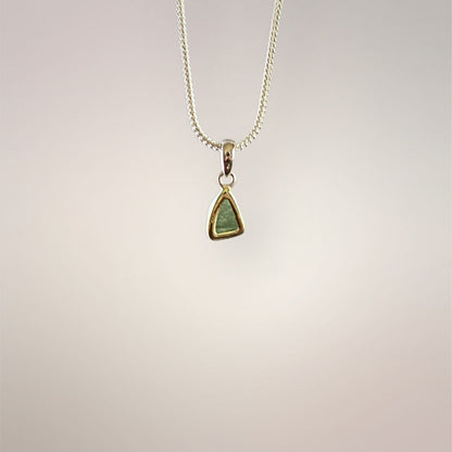 Back view of a small natural green Moldavite pendant in a .925 sterling silver setting on a silver-tone chain.