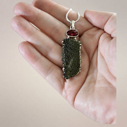 Hand-held scale view of the 60 mm Angel Chime Moldavite and rubellite pendant with natural texture and .925 silver setting.